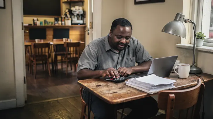 A café owner working out his costs with a calculator after closing