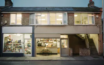 Small businesses on a high street with their lights on at dusk
