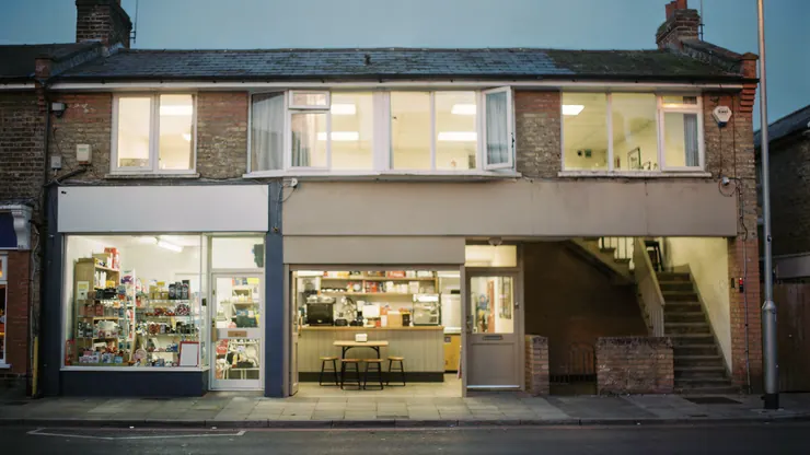 Small businesses on a high street with their lights on at dusk