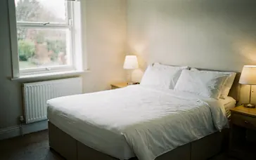 Empty hotel bedroom with bedside lamps on in the early morning