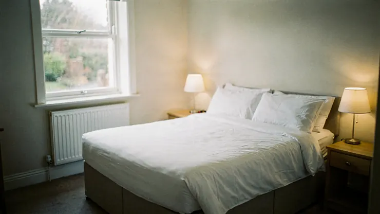 Empty hotel bedroom with bedside lamps on in the early morning