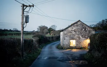 Electricity pole with a transformer beside a country lane at dusk
