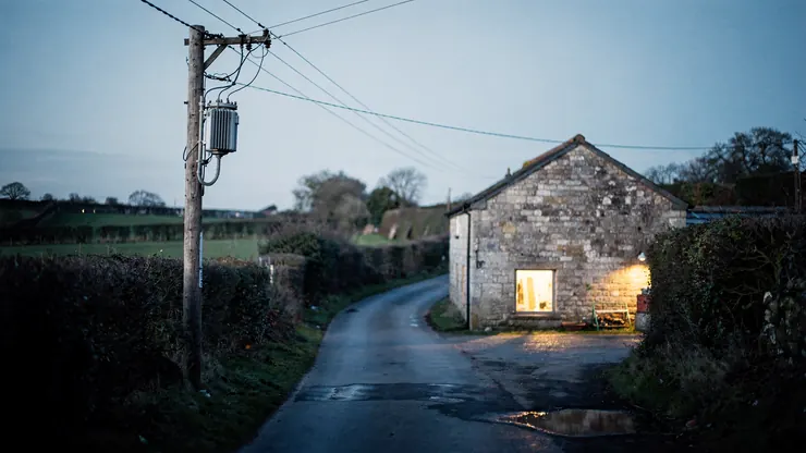 Electricity pole with a transformer beside a country lane at dusk